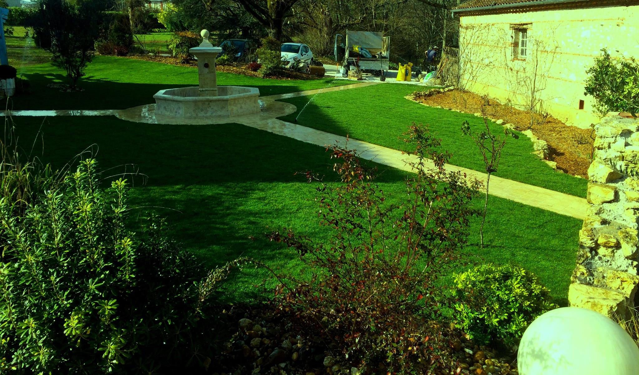 Jardin verdoyant Pescay Gazon avec fontaine octogonale, maison en pierre et allées dans le Tarn,